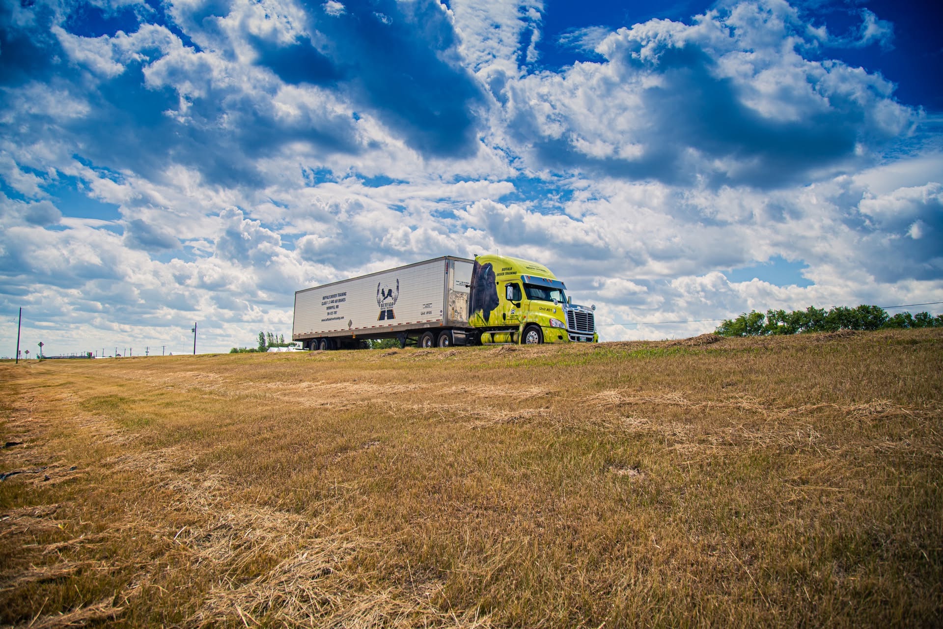 A yellow Buffalo Driver Training truck beneath an open prairie sky